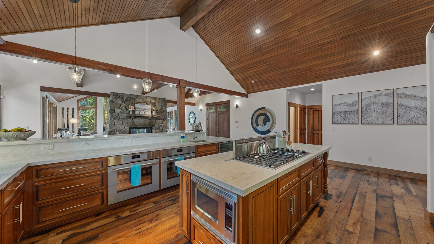 Your chef's kitchen awaits with a gleaming marble island, professional gas range, and soaring wood-planked ceilings that add rustic warmth to this elegant space.