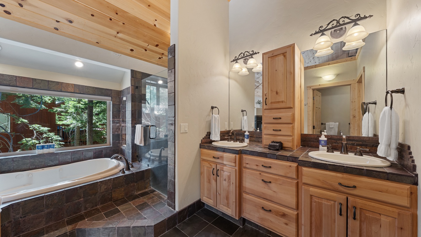Unwind in your private spa-inspired bathroom, where rustic wood meets elegant stone, complete with a soaking tub and views of the peaceful greenery outside.