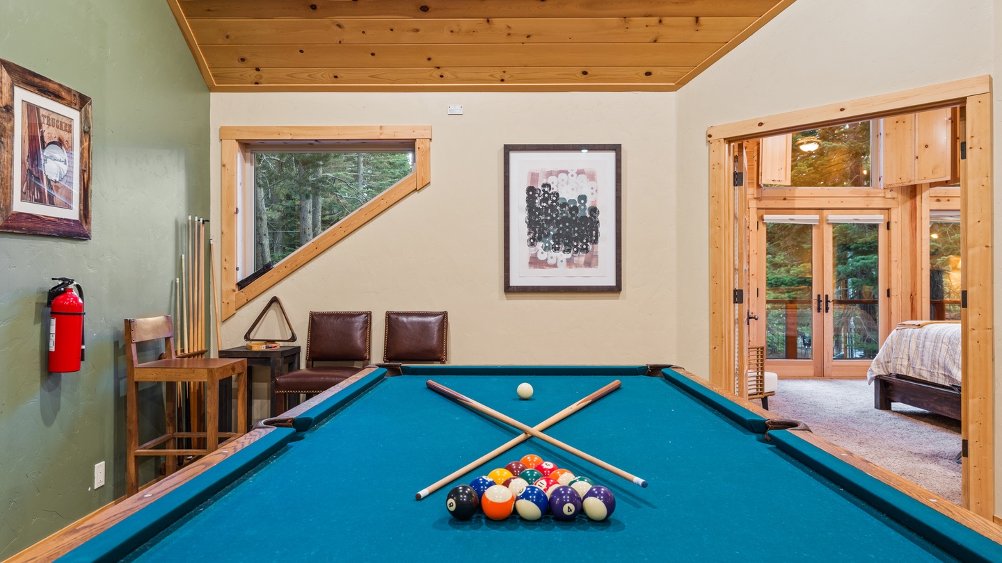 Challenge friends to a game of pool in your own private recreation room, featuring warm wood accents and natural light streaming through floor-to-ceiling windows overlooking the surrounding forest.