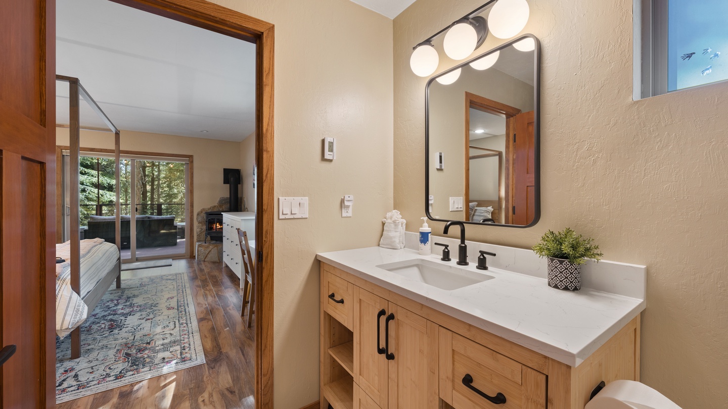 Step into your private bathroom with warm wood tones, a clean white vanity, and thoughtful touches like fresh greenery—everything you need to feel refreshed after a day exploring the mountains.