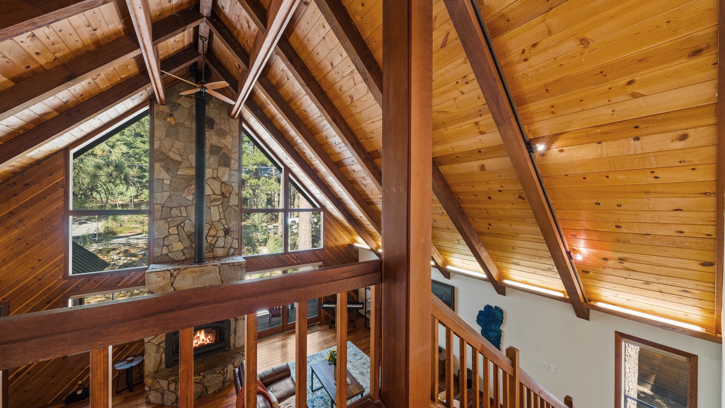 Soaring wooden beams and a stunning stone fireplace create a warm, airy retreat where you can relax beneath vaulted ceilings and natural light streaming through tall windows.