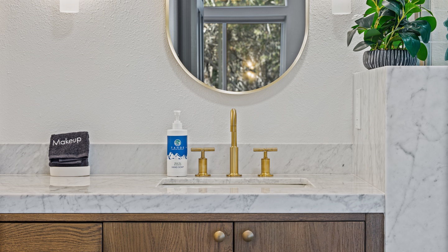 Step into your private sanctuary, where elegant marble meets warm wood cabinetry and gleaming gold fixtures. Fresh touches await your arrival in this thoughtfully designed space.