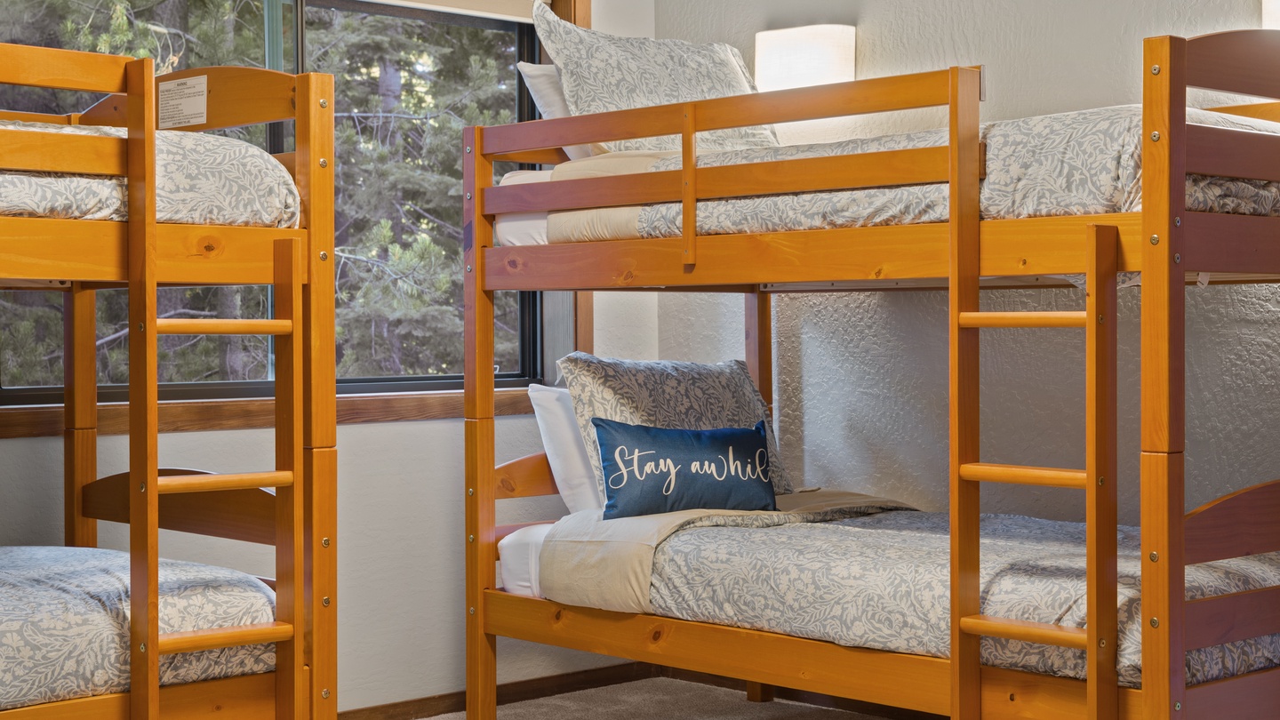 Bunk beds provide flexible sleeping arrangements with a warm natural finish. Natural light streams through the window, creating an inviting space for restful nights.