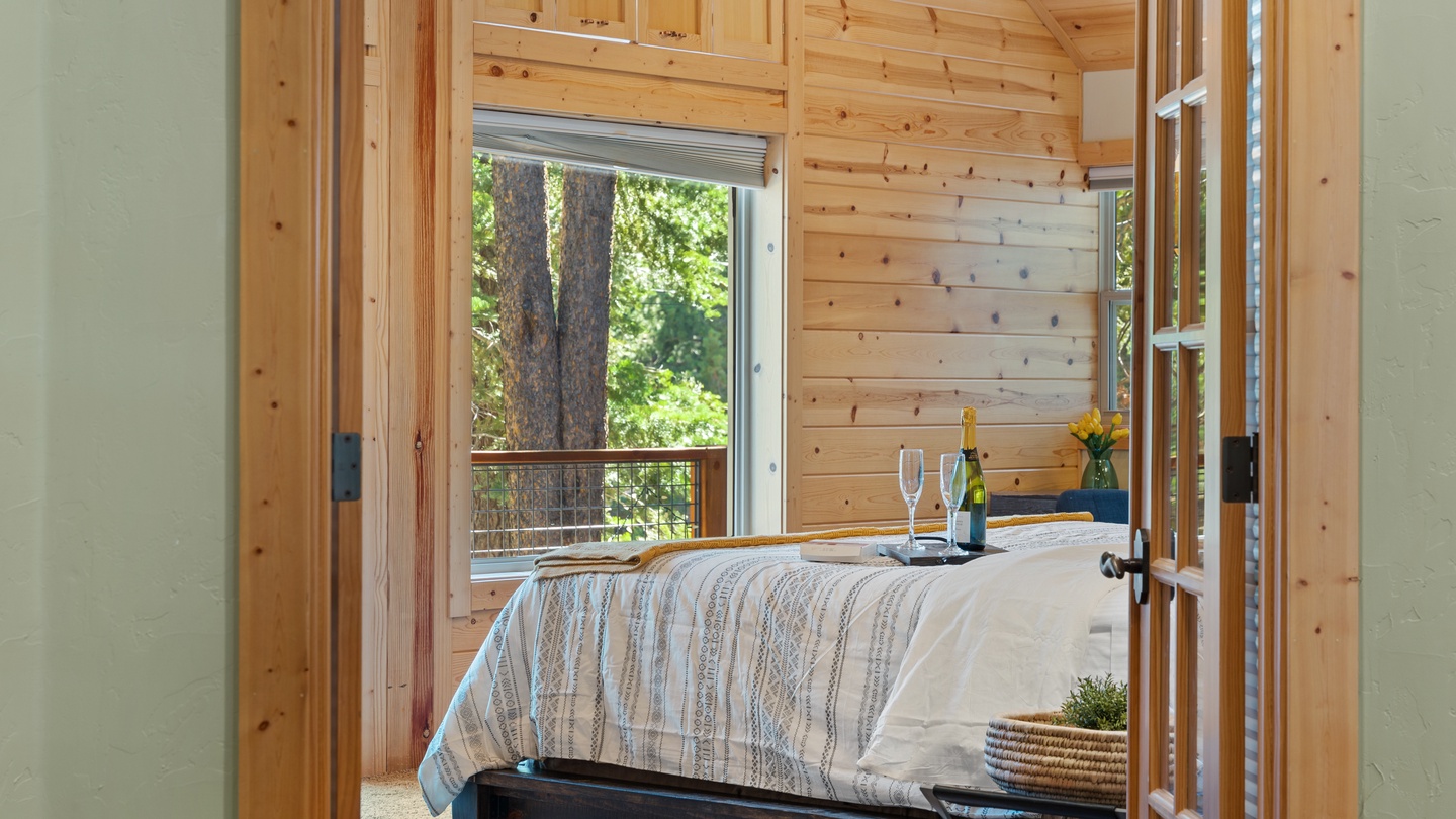 Step into your cozy bedroom retreat, where warm pine walls and a peaceful forest view through the window create the perfect mountain escape.