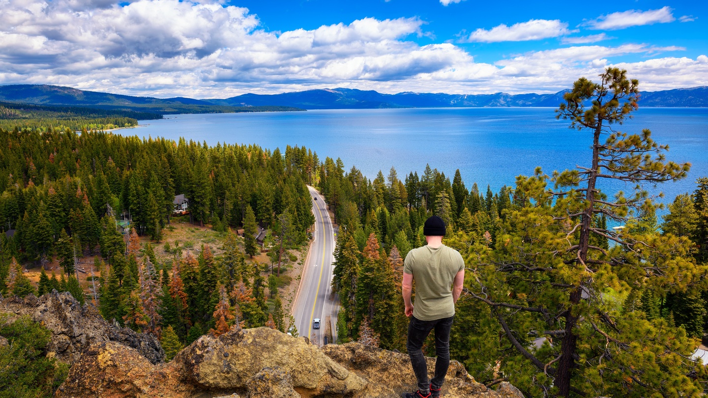 Stunning aerial perspective showcases the pristine lake, winding mountain roads, and dense forest landscape surrounding the property area.