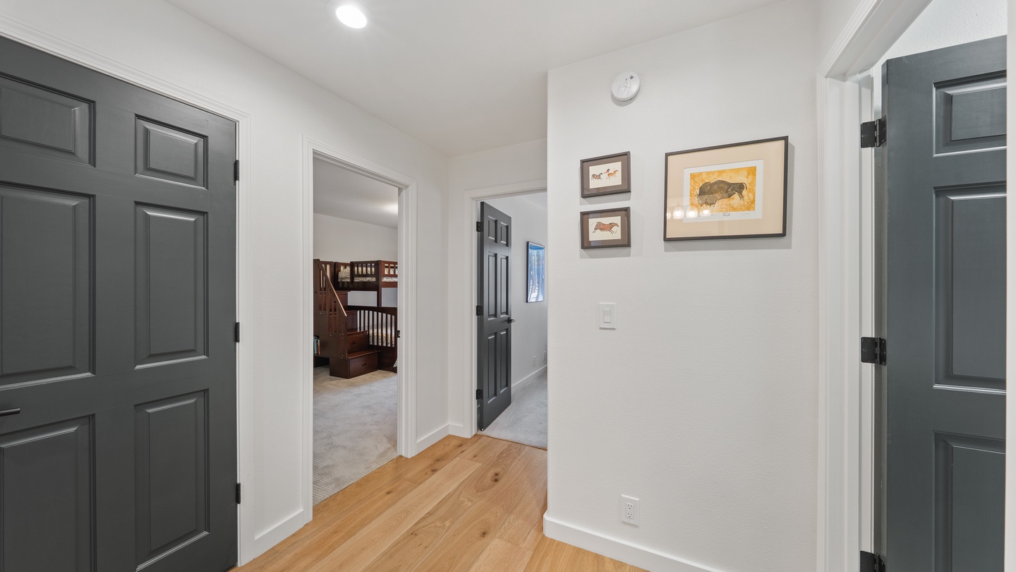 Your private hallway connects bedrooms with warm hardwood underfoot and charming artwork adding a homey touch to your stay.