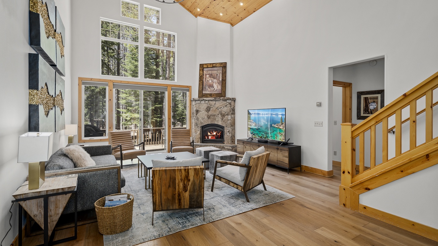Curl up by your stone fireplace in this airy, light-filled living space with soaring vaulted ceilings and forest views just beyond your glass doors.