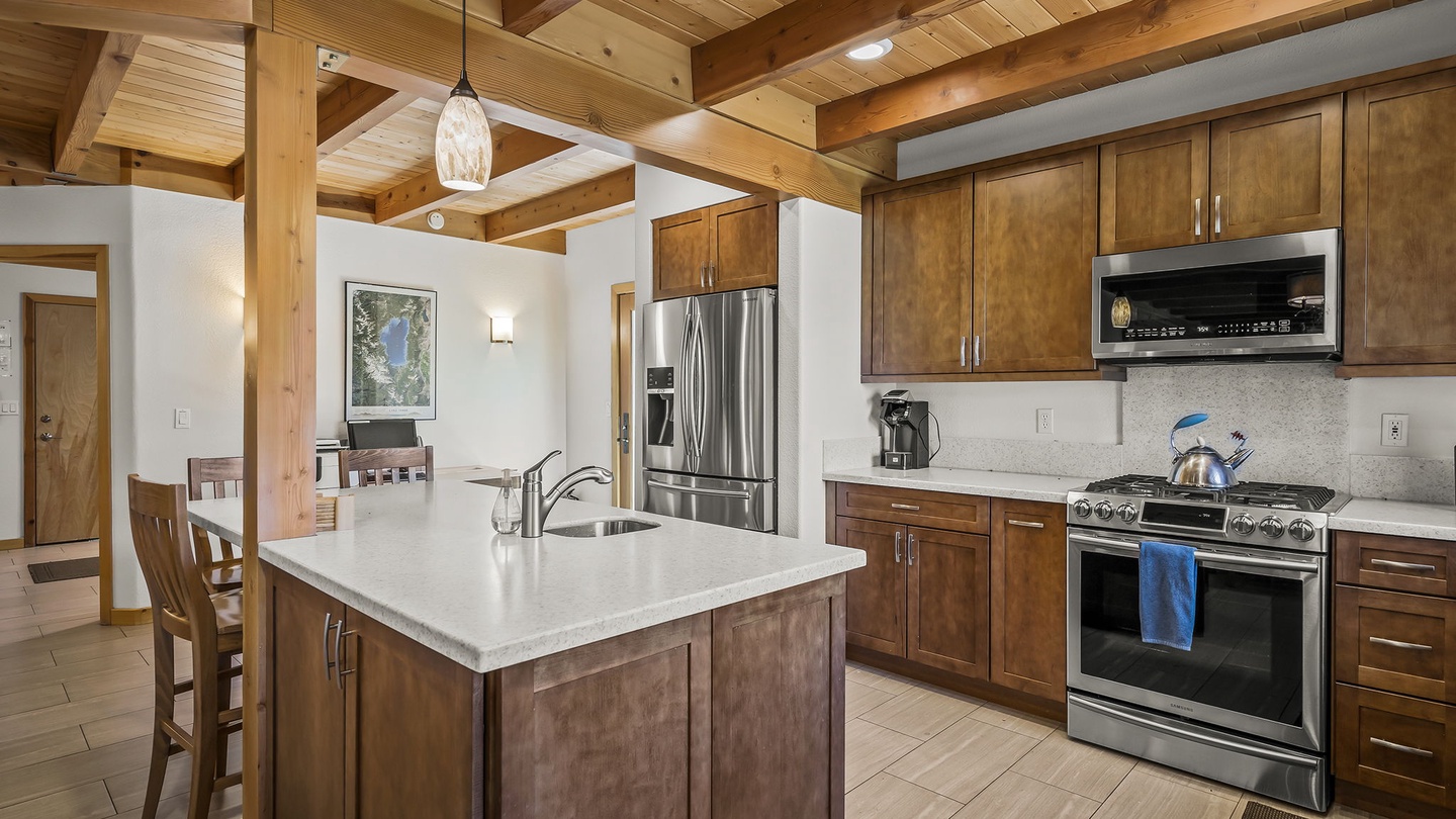 Step into your gourmet kitchen with soaring timber beams overhead, gleaming stainless appliances, and a spacious island perfect for morning coffee or evening prep.