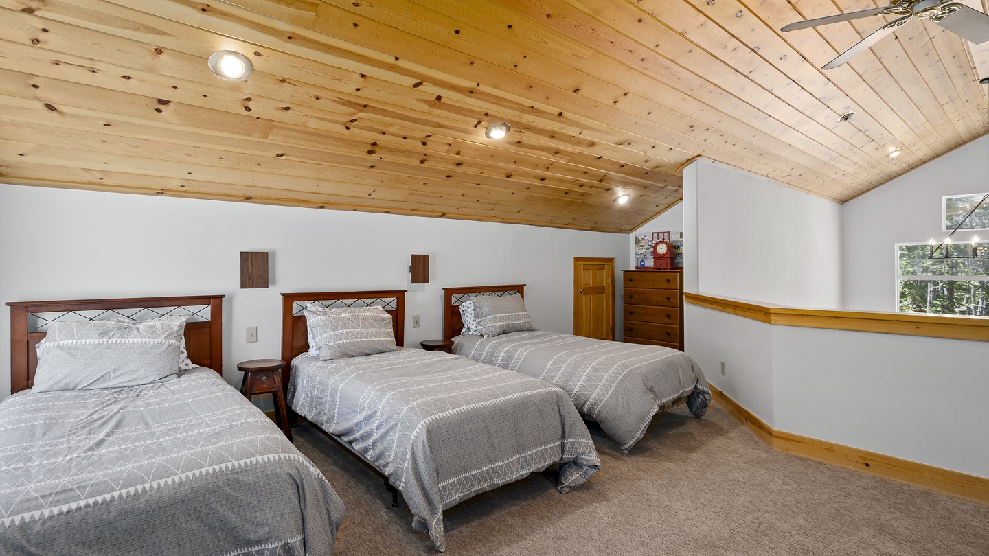 Stretch out in this spacious bedroom with three comfortable beds and a beautiful wood-paneled ceiling. Natural light fills the room, creating a warm, restful retreat after a day of adventure.
