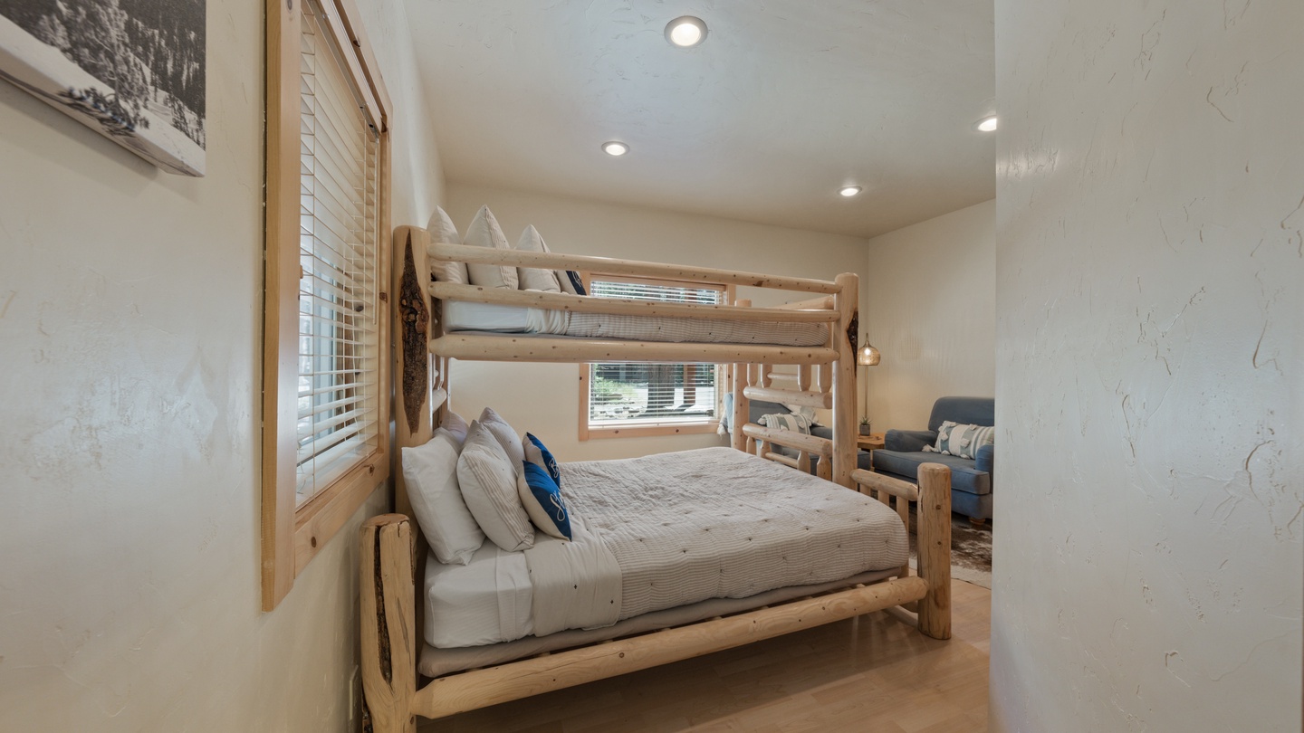Your cozy bedroom features a charming bunk bed with rustic wood framing, perfect for families. Natural light streams through the windows, highlighting the warm tones and comfortable bedding that invite restful nights.