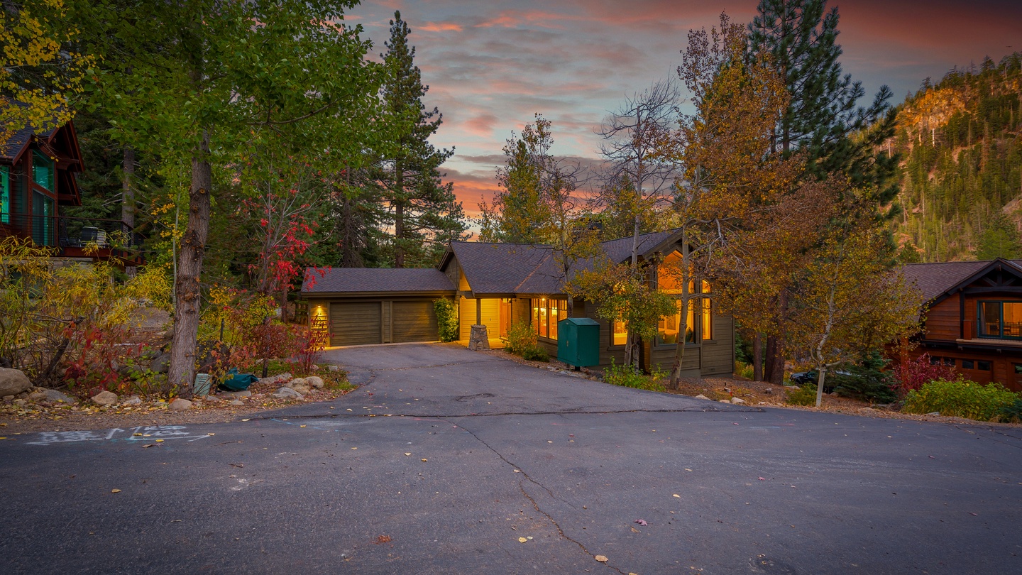 Nestled among the trees with warm evening light illuminating the wood-sided exterior, this inviting mountain retreat offers autumn charm and peaceful surroundings as the day draws to a close.