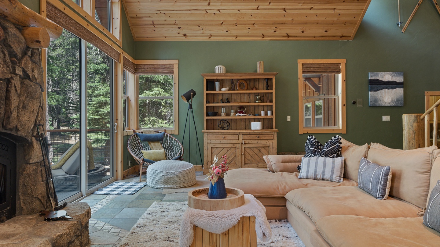 Sink into the plush sofa and let the forest views soothe you through floor-to-ceiling windows. The vaulted wood ceiling adds rustic warmth to your mountain retreat.