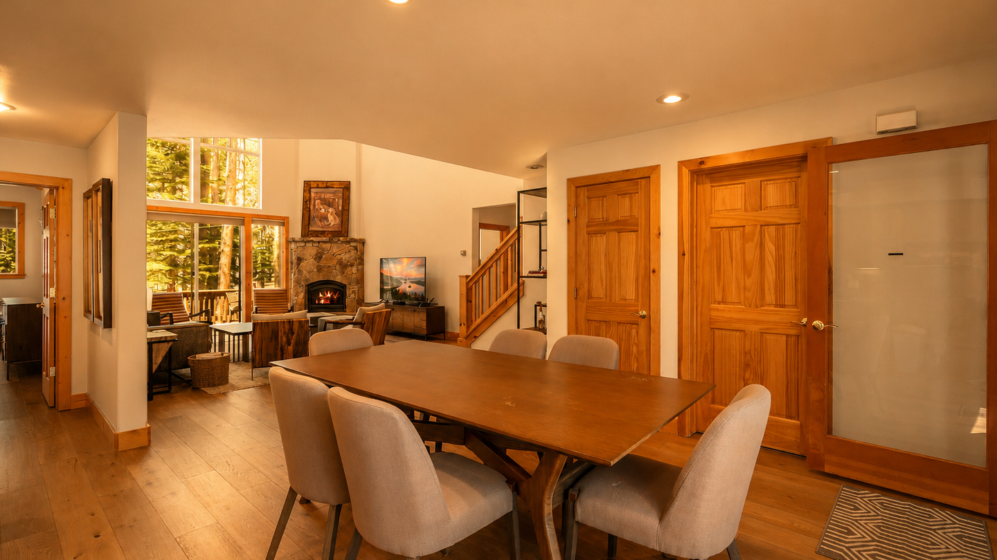 Gather around the dining table and plan your next adventure while sunlight filters through the tall windows. A cozy fireplace waits in the living room beyond, ready to warm your evenings.