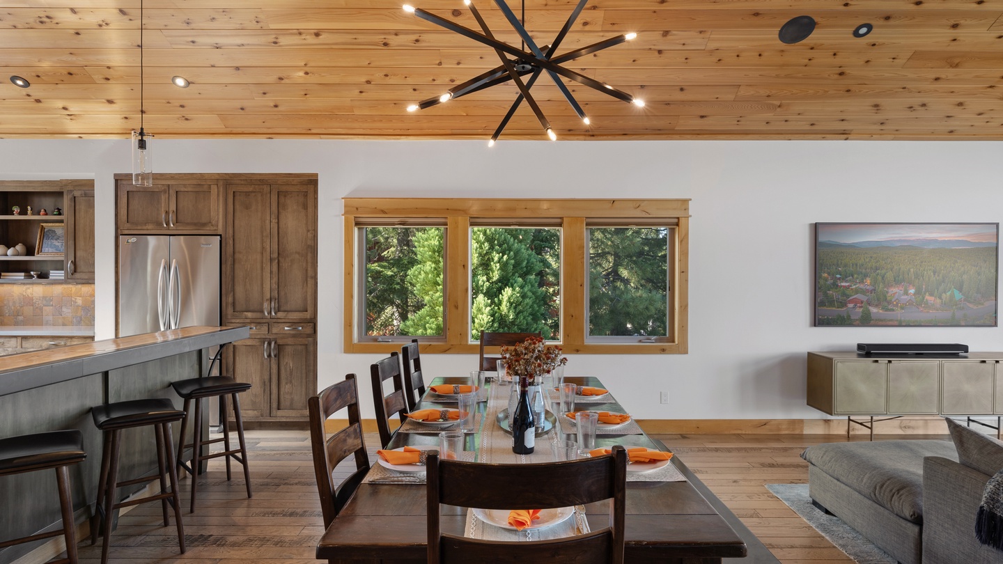 Gather around this warm, wood-accented dining space beneath soaring timber ceilings. Your chef-ready kitchen opens to a table set for memorable meals with garden views through oversized windows.