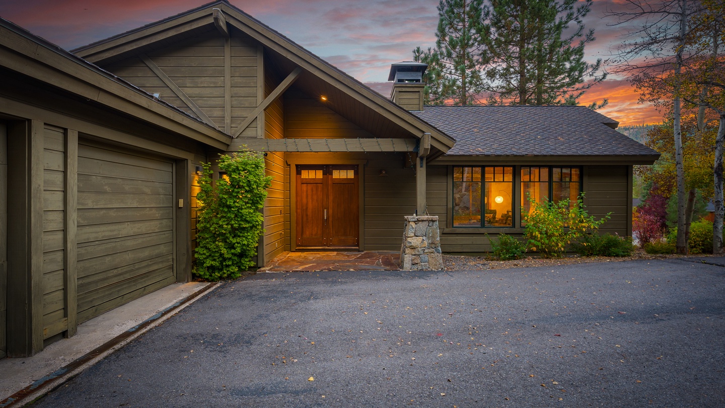 A welcoming mountain retreat framed by pines and autumn colors, captured during a stunning sunset. The warm glow from the windows invites relaxation after a day exploring the natural surroundings.