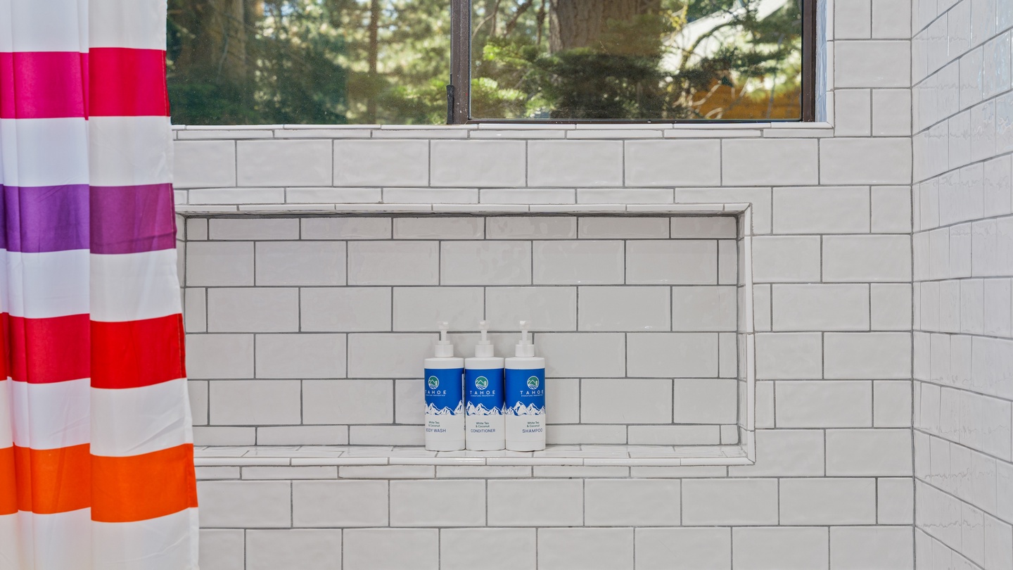 Natural light floods your private bathroom through a large window overlooking the surrounding forest, while premium toiletries await you in the tiled shower niche.