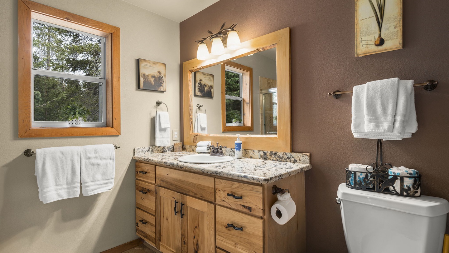 Freshen up in your stylish bathroom featuring granite countertops, warm wood vanity, and fluffy towels waiting for you.