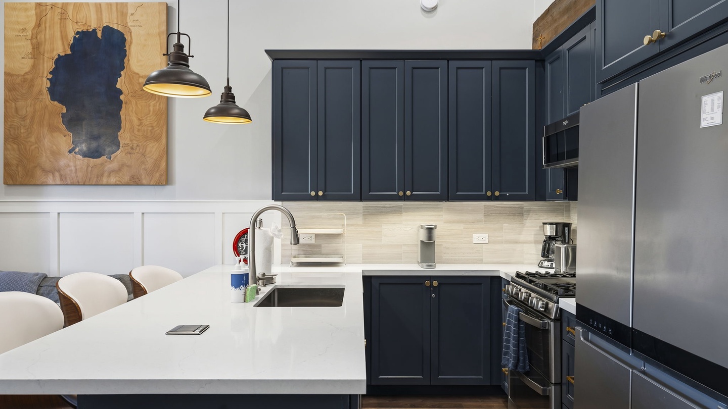Cook your favorite meals in this stylish kitchen featuring sleek navy cabinetry, modern appliances, and a convenient breakfast bar.