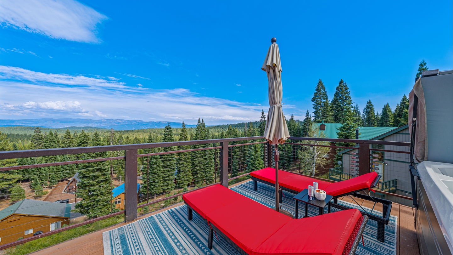 Unwind on your private deck with two inviting lounge chairs, a patio umbrella for shade, and sweeping forest views stretching to distant mountains—your peaceful mountain escape awaits.