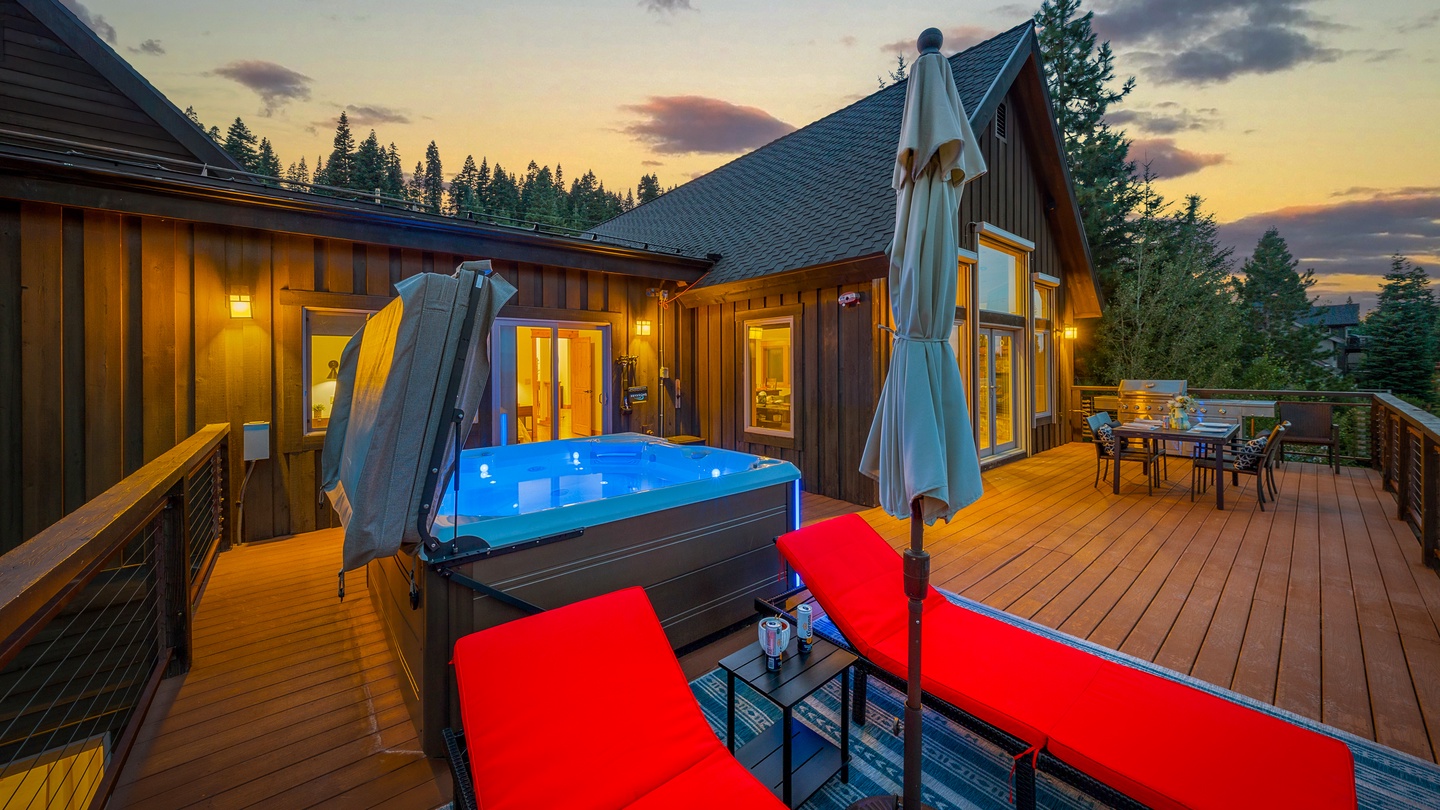 Stunning mountain retreat features a spacious deck with hot tub, lounge seating, and dining area overlooking towering pines—your perfect sunset sanctuary awaits.