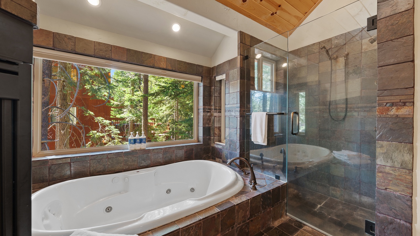 Unwind in your private spa-like sanctuary with a jetted soaking tub and walk-in shower, framed by forest views through the window.