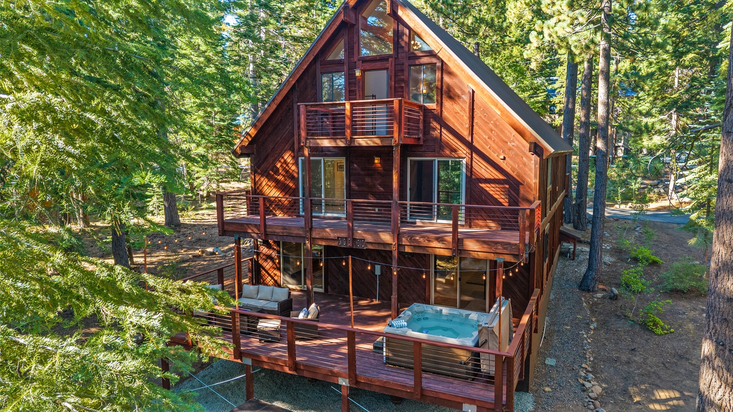 A stunning cedar cabin rises three stories through the forest canopy, featuring expansive wraparound decks on each level and a relaxing hot tub for your mountain retreat.