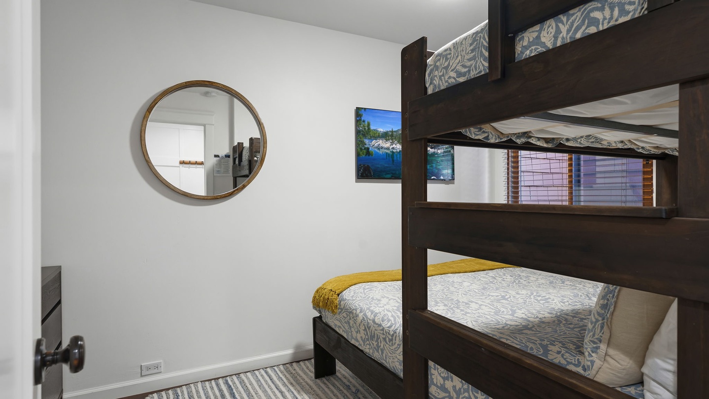 Your bunk bed room features cozy bedding and a round mirror, perfect for families or groups sharing memories together.