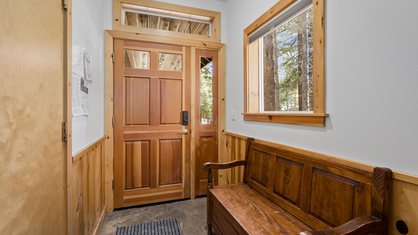 Step inside to beautiful warm wood tones and natural light streaming through large windows. Your cozy retreat awaits with a welcoming bench and serene forest views.