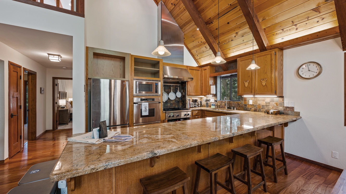 This spacious gourmet kitchen invites you to gather around the stunning granite island, where you can cook together and share stories under soaring wooden cathedral ceilings bathed in warm natural light.