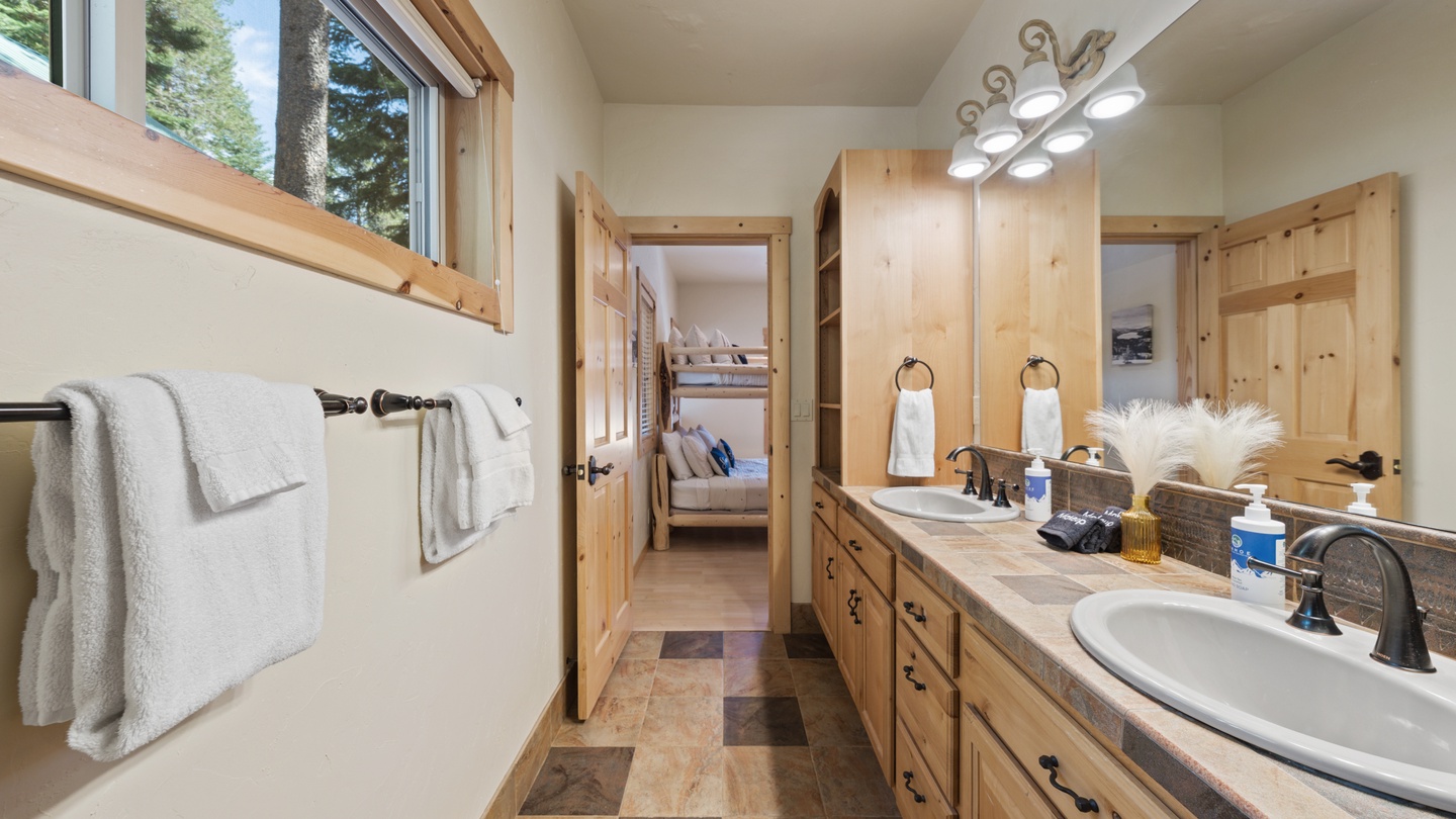 Step into your private bathroom with natural light streaming through the windows, warm wood accents, and a Jack-and-Jill layout connecting to the bedroom. Fresh towels and thoughtful finishes make it feel like a mountain retreat.