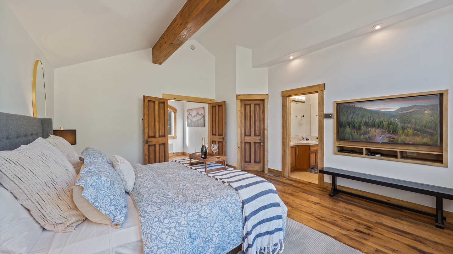 Unwind in your spacious bedroom with vaulted ceilings, warm wood beams, and a plush bed inviting restful nights. Your ensuite bathroom and entertainment setup ensure comfort and relaxation.