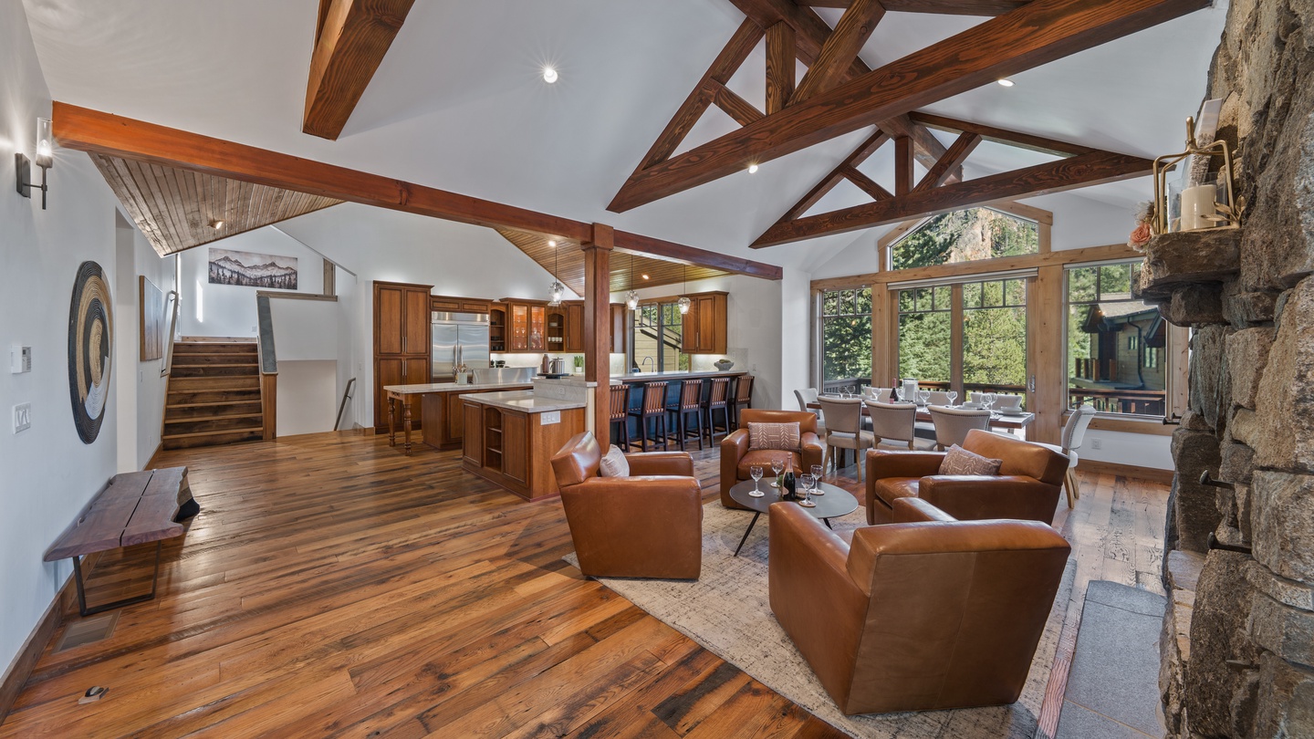 Gather around the stone fireplace in your soaring great room, where exposed timber beams frame views of lush greenery. Elegant seating flows naturally into a gourmet kitchen perfect for entertaining.