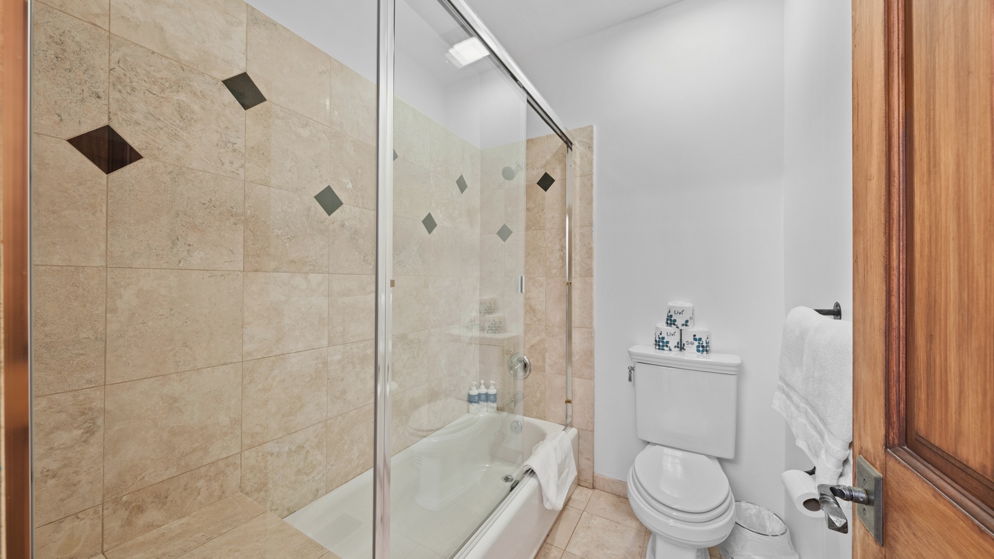 Your private bathroom features elegant travertine tiling with decorative diamond accents, a deep soaking tub, and crisp white linens—everything you need to unwind after your day exploring.
