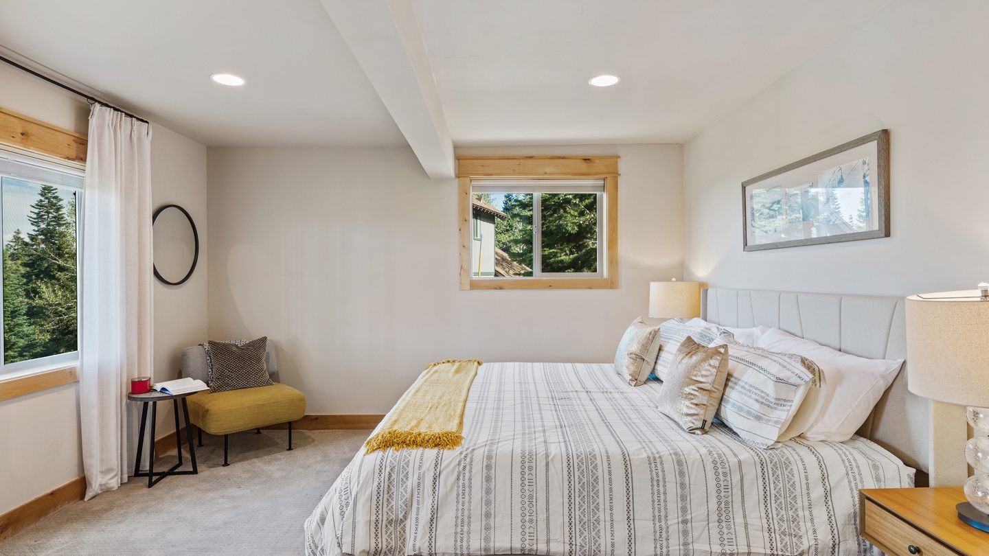 Sink into crisp linens and let natural light fill your bright, peaceful bedroom retreat. The plush queen bed invites restful sleep, while windows framing evergreen views keep you connected to the surrounding beauty.