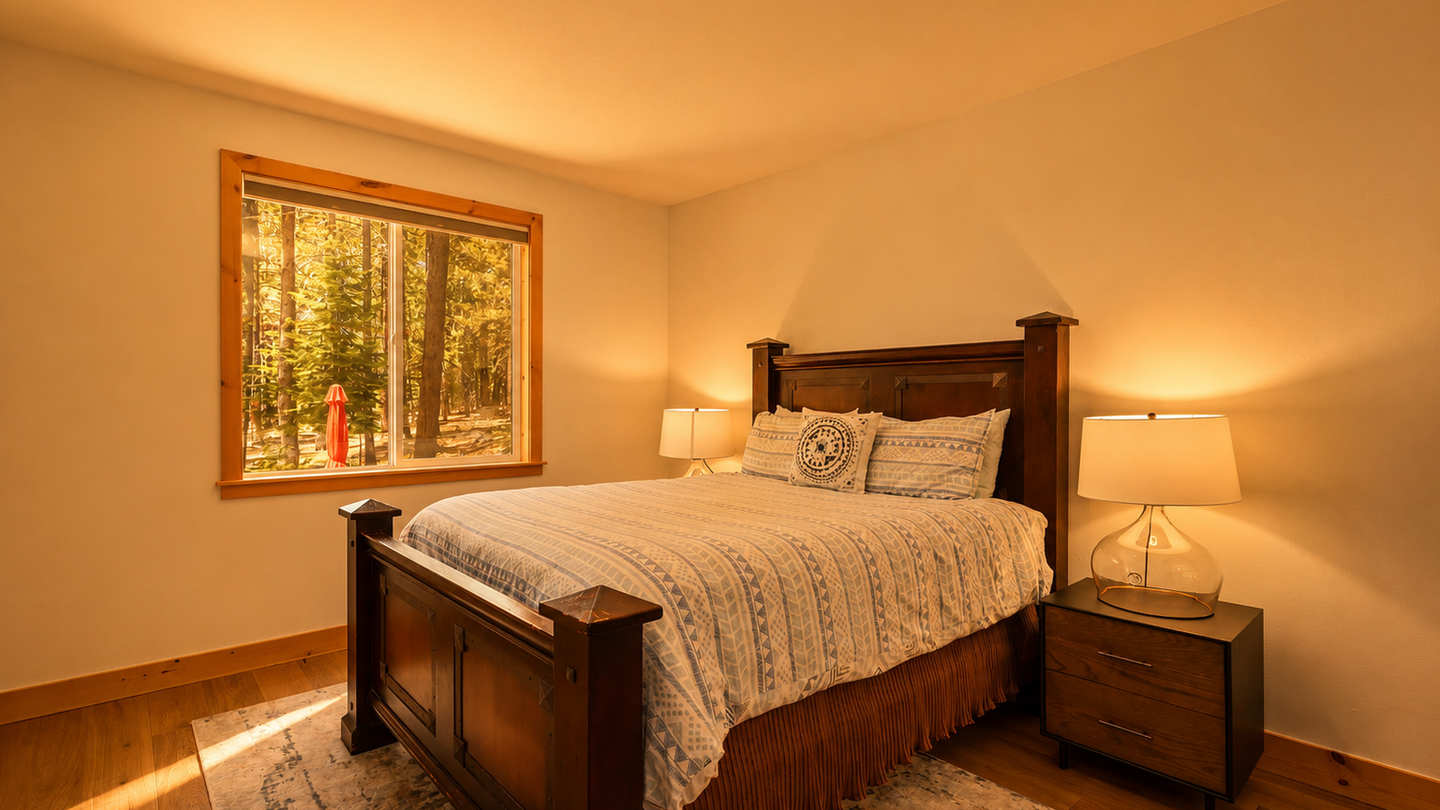 Picture yourself unwinding here after a day of adventure. Warm wood tones and soft lighting create a peaceful retreat. The window frames serene forest views, bringing nature right to your bedside for truly restful nights.