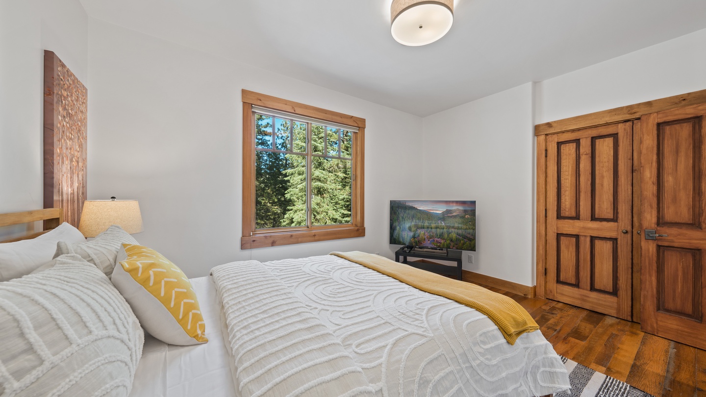 You'll love waking up in this bright, peaceful bedroom with its warm wood accents and forest views framing your mornings in natural beauty.