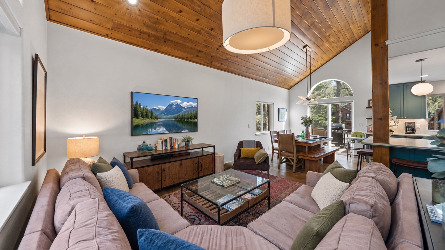 Sink into plush sofas beneath warm wood ceilings, where natural light streams through arched windows inviting you to unwind in this cozy mountain retreat.