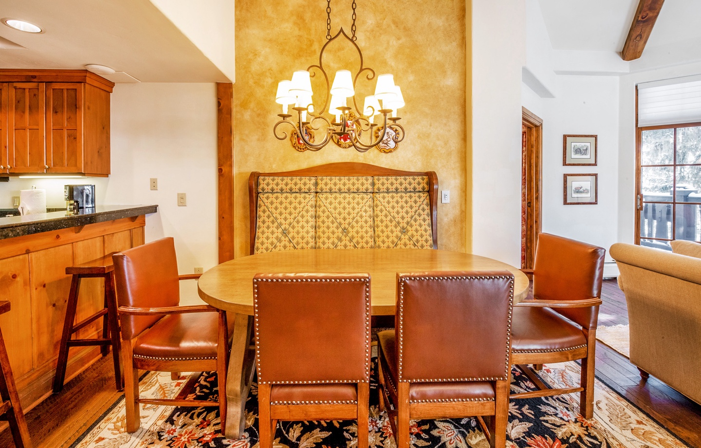 Gather around your private dining table beneath a warm chandelier, where rich wood tones and leather seating create an inviting space for memorable meals together.