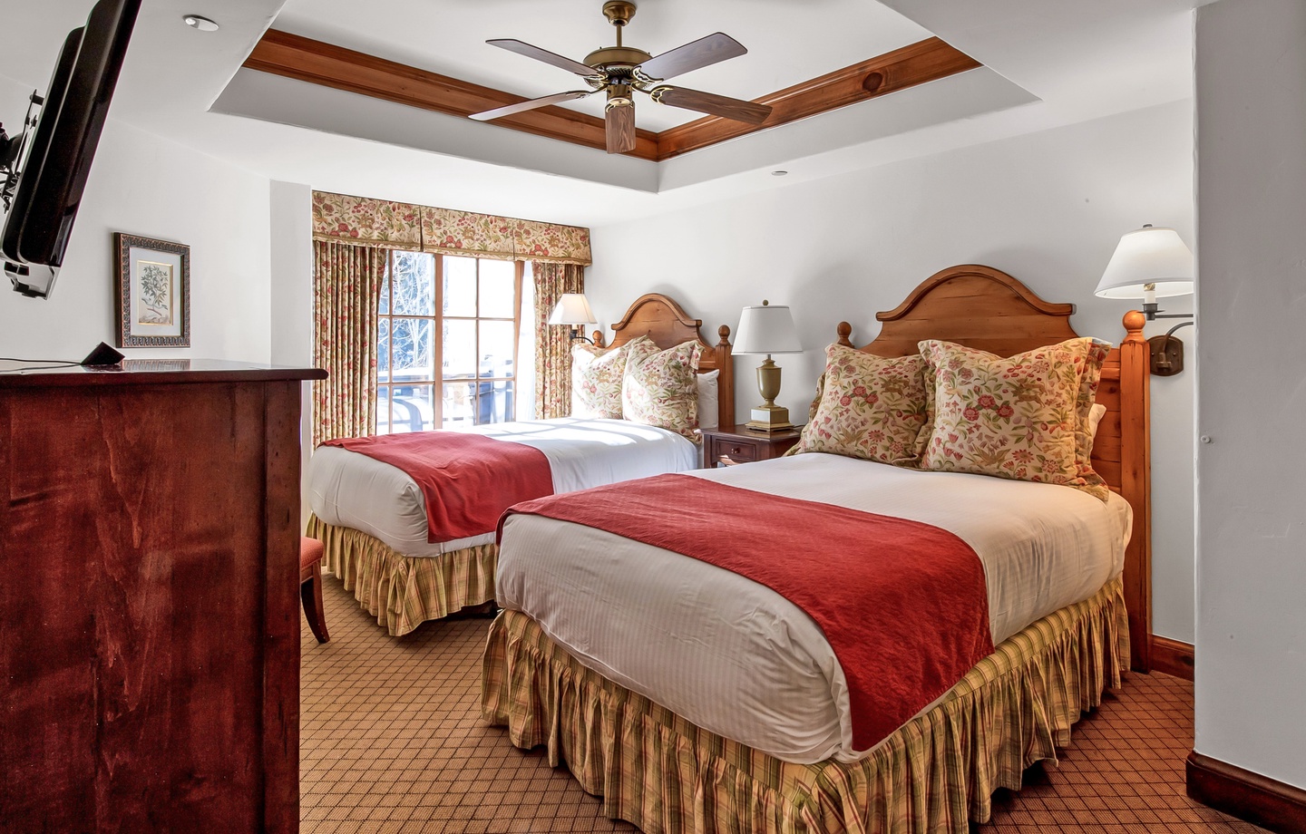 Rest easy in this warm bedroom with two plush beds dressed in crisp linens and coral throws. Elegant wood furnishings and a tray ceiling add charm while you unwind.
