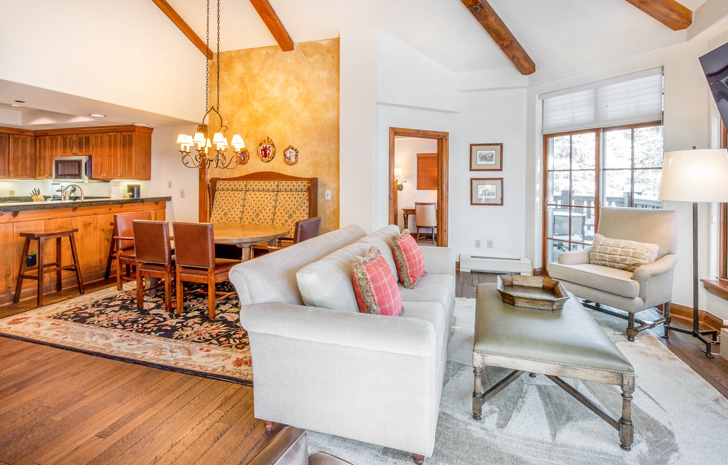 Step into your inviting open-concept living space, where rustic wood beams meet elegant furnishings. Curl up on plush sofas or gather around the dining table, all bathed in natural light from expansive windows.