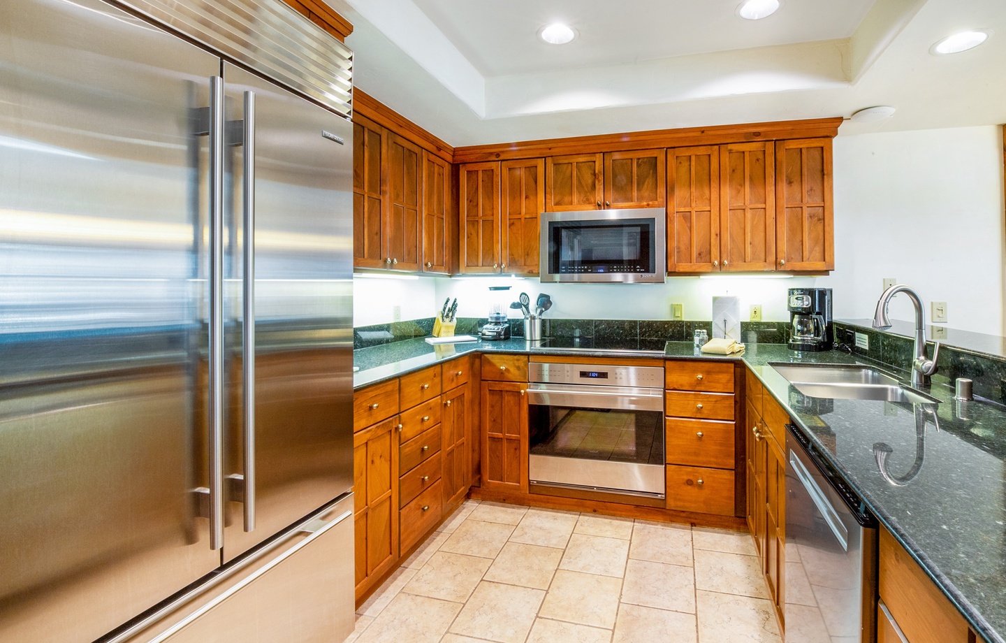 Your fully equipped kitchen features rich wood cabinetry, gleaming granite countertops, and stainless steel appliances—perfect for preparing meals or brewing your morning coffee in style.