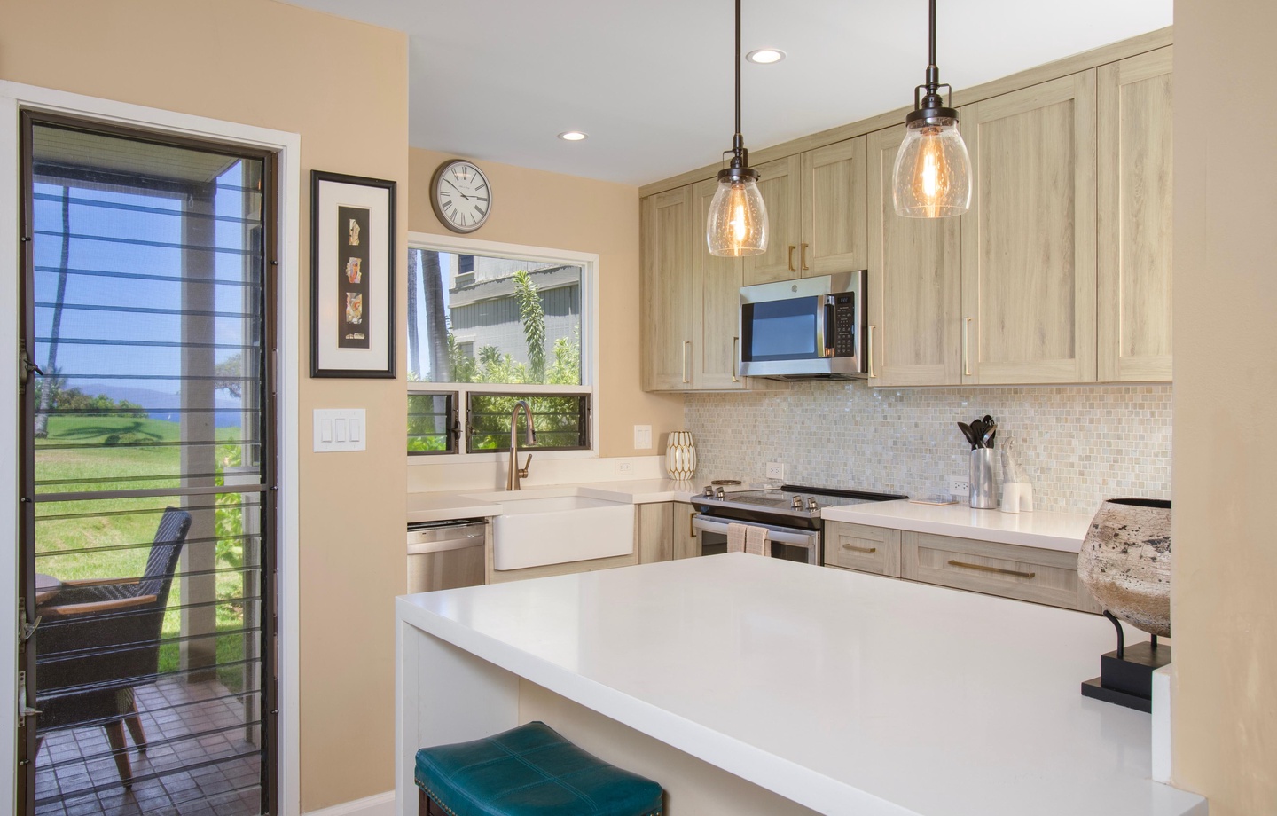 Gather around the bright island with stylish pendant lighting and farmhouse charm. Sleek countertops and natural light make meal prep a breeze, while the door opens to peaceful outdoor views.