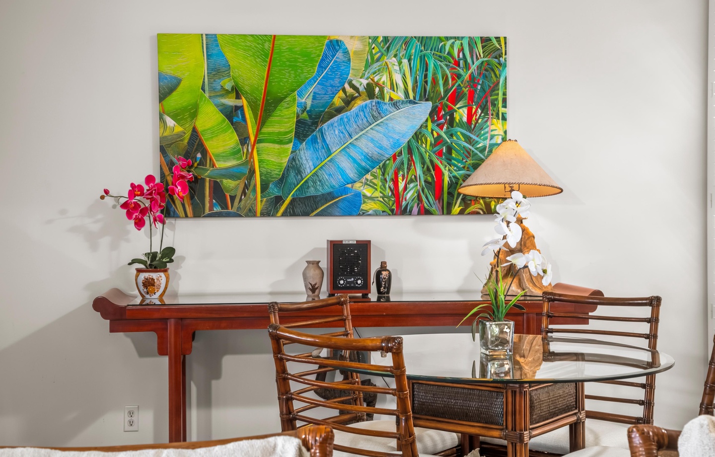 A warm dining area where vibrant tropical artwork sets a welcoming tone for your meals. Rich wood furniture and tasteful décor invite you to gather and relax.