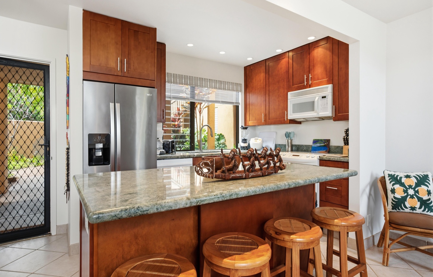 Your gourmet kitchen features gleaming granite counters, stainless steel appliances, and a welcoming breakfast bar with tropical-style seating—perfect for morning coffee or gathering with loved ones.