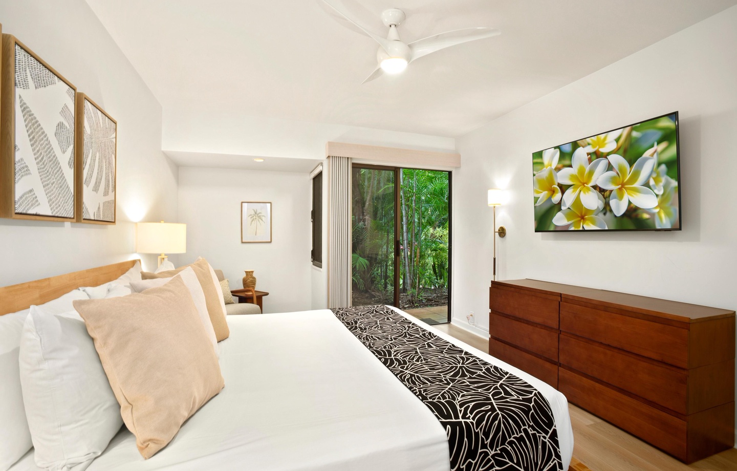 Sink into crisp white linens in your peaceful bedroom retreat, where soft lighting and tropical greenery just outside your door set the scene for restful nights.