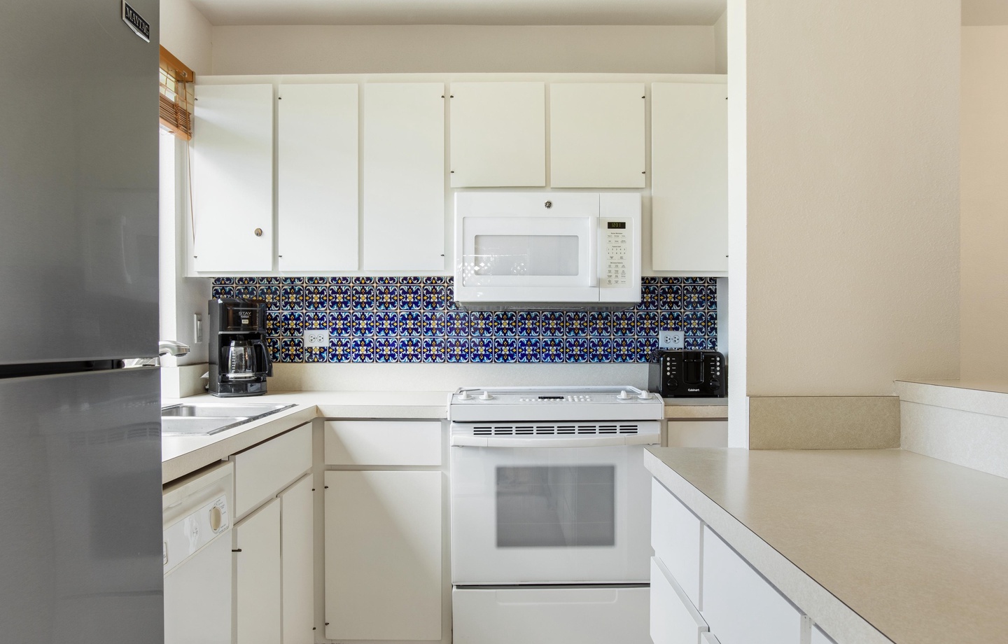Your fully equipped kitchen features vibrant decorative tile backsplash that adds colorful character to the bright, functional space where you'll prepare meals during your stay.