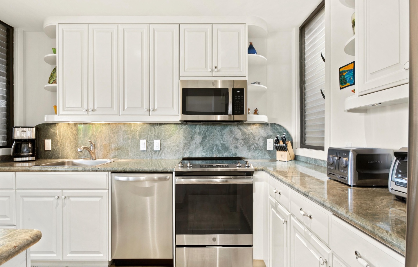 Step into your fully equipped kitchen where cooking feels effortless. Crisp white cabinetry, stainless steel appliances, and elegant stone countertops create a bright, welcoming space for preparing vacation meals together.