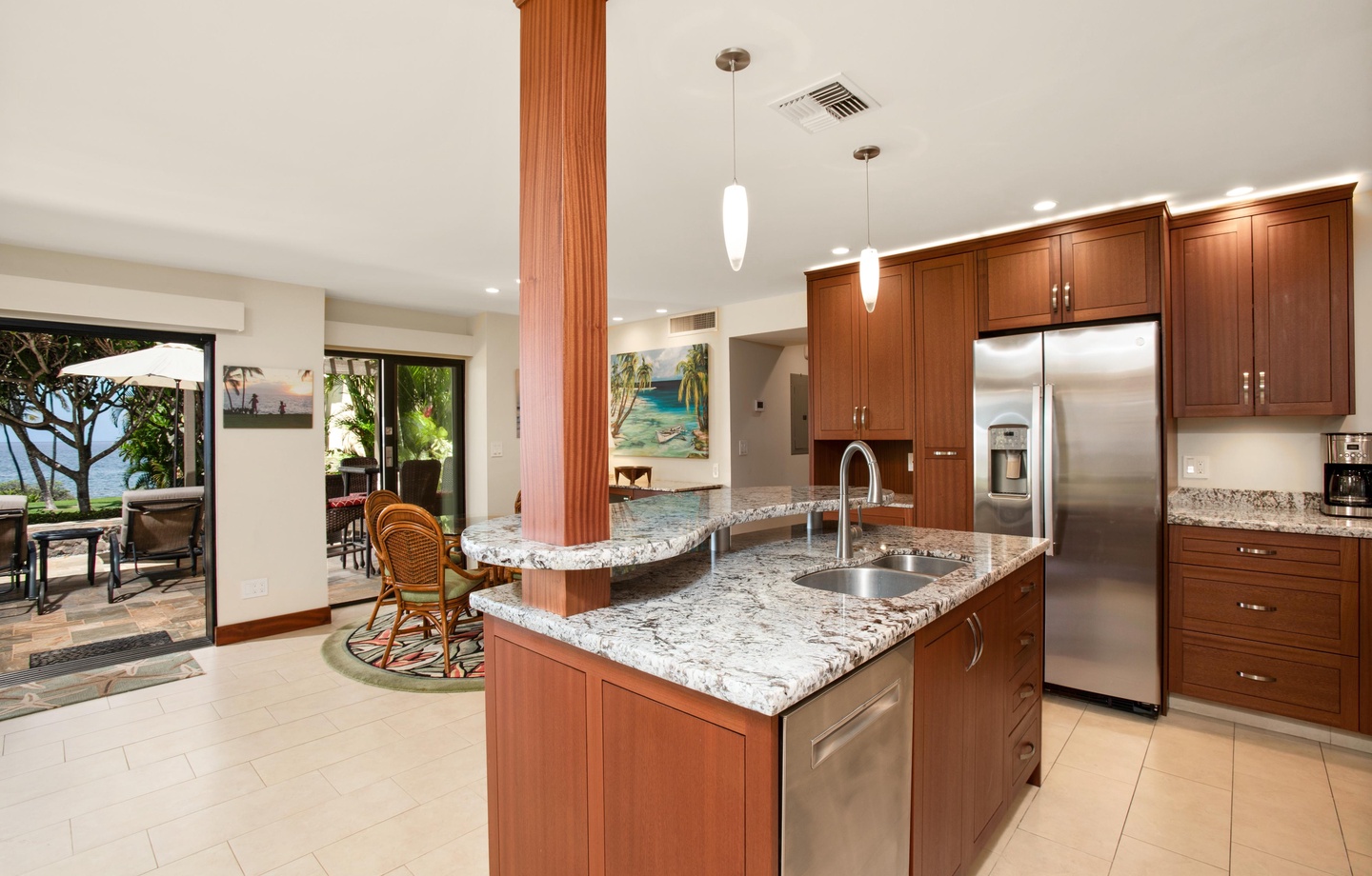 Your gourmet kitchen features granite counters, stainless appliances, and a curved island perfect for gathering. Step through open doors to your private outdoor dining area with ocean breezes.