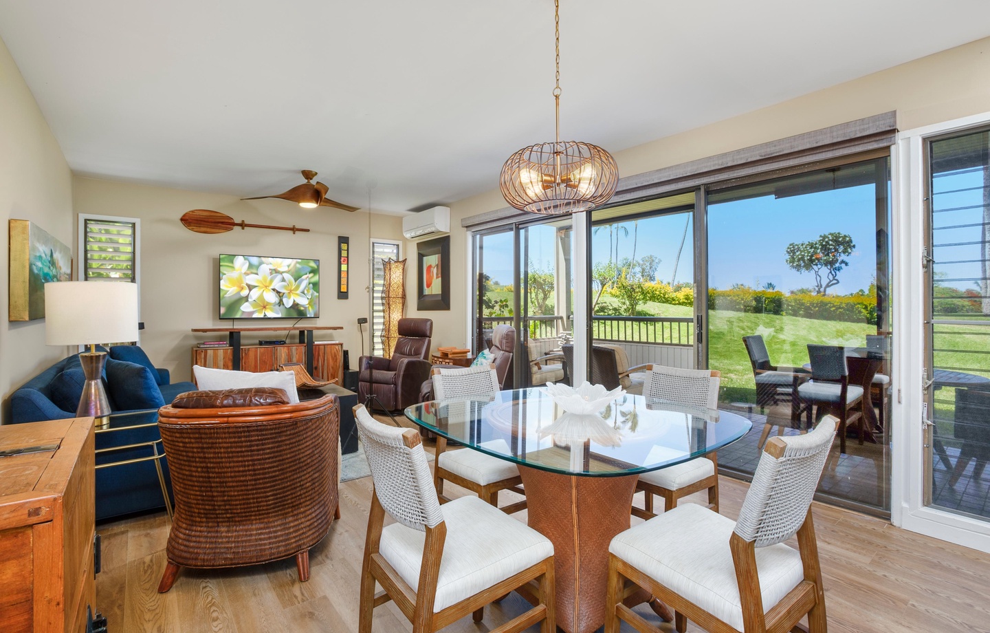 Gather around the elegant glass dining table with lush green fairway views framing every meal. The open living space flows seamlessly to your private lanai, perfect for morning coffee or sunset cocktails overlooking paradise.