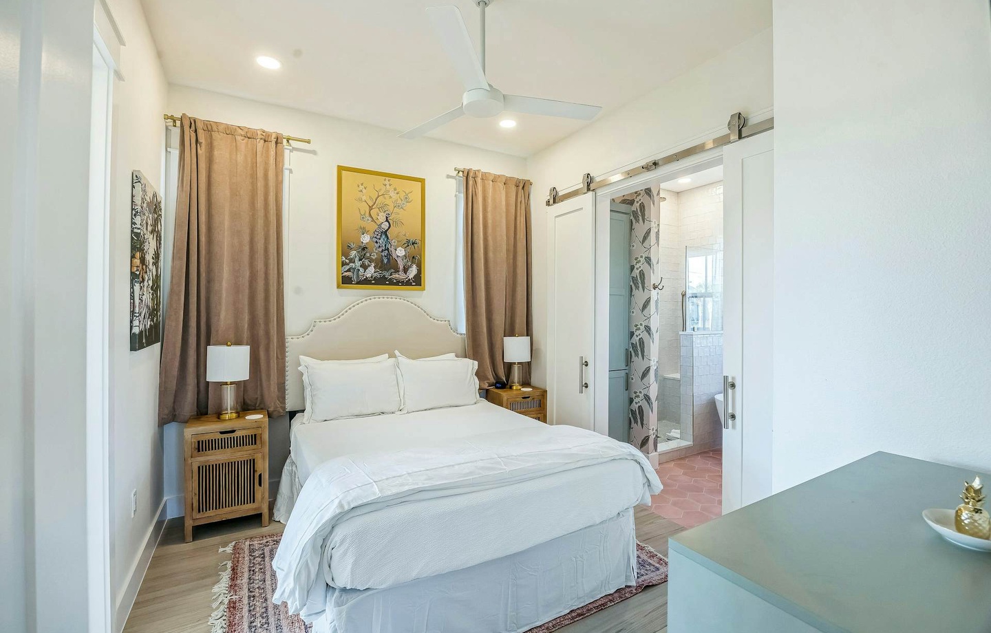 Step into your serene retreat where crisp linens invite restful sleep. A stylish barn door reveals your private en-suite, while soft natural light and a gentle ceiling fan keep you comfortable year-round.